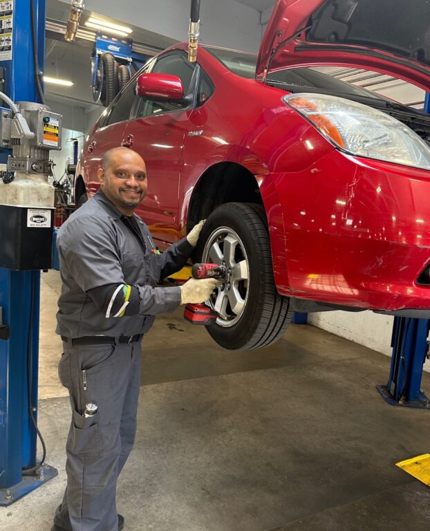 Earthling Automotive service technician removing tire and wheel of a Toyota Prius for alignment