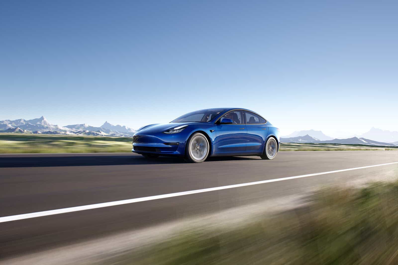 Image showcasing Tesla model 3 driving on a paved highway road