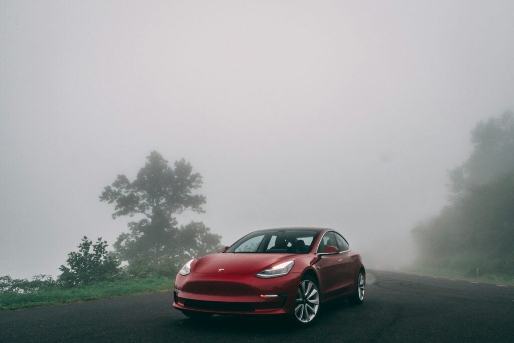 A red Tesla surrounded by mist